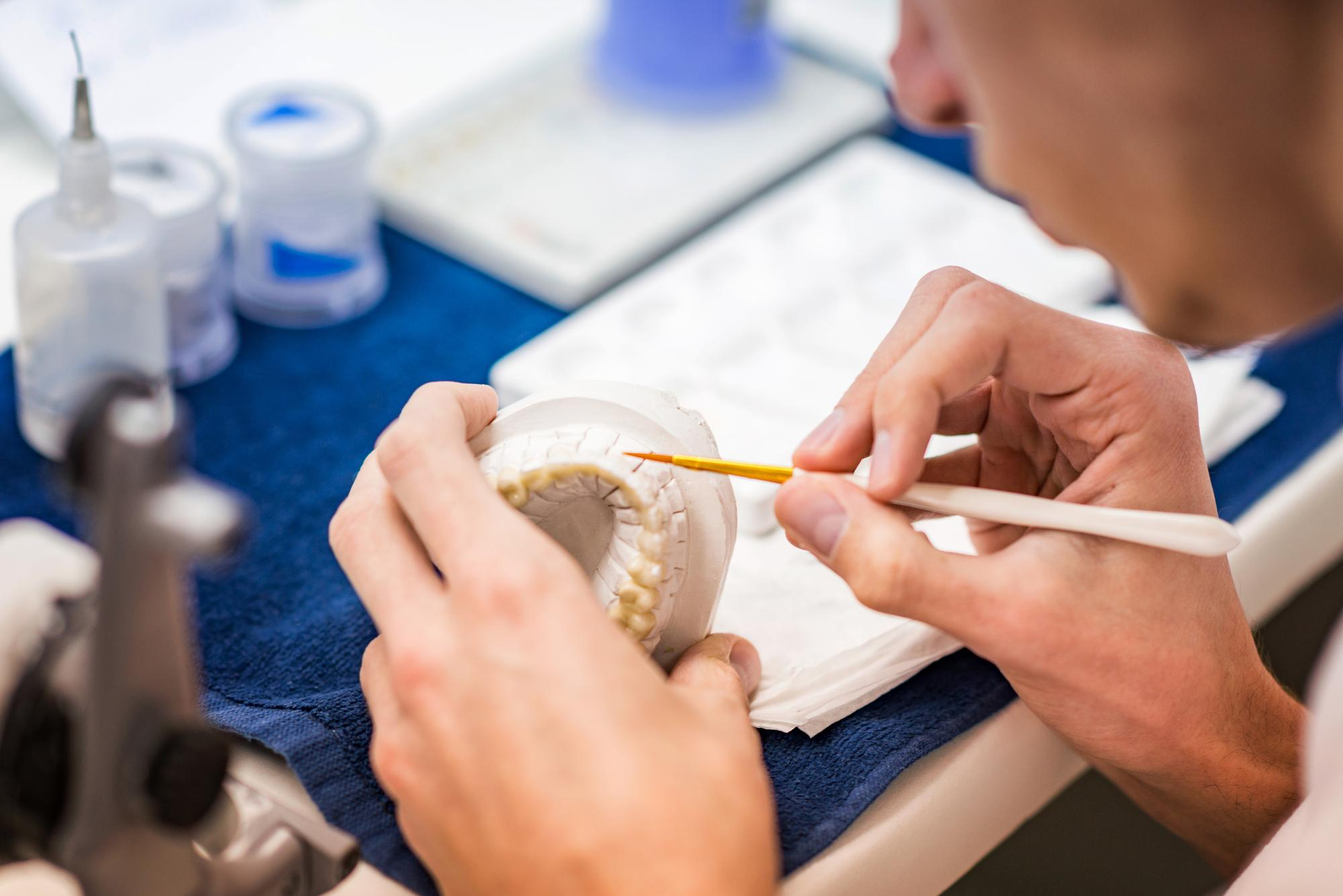 Mondzorgspecialist die een kunstgebit kleurt